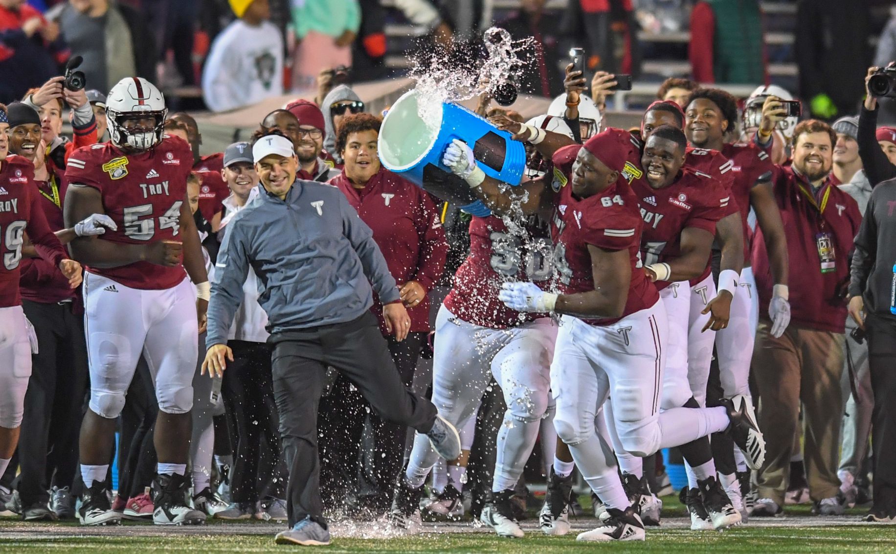 Neal Brown evades a celebratory postgame water bath from his players after defeating Buffalo in the 2018 Dollar General Bowl.